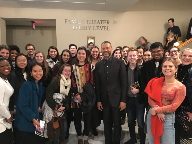 Group of students and professors standing inside with a sign in the background that reads 