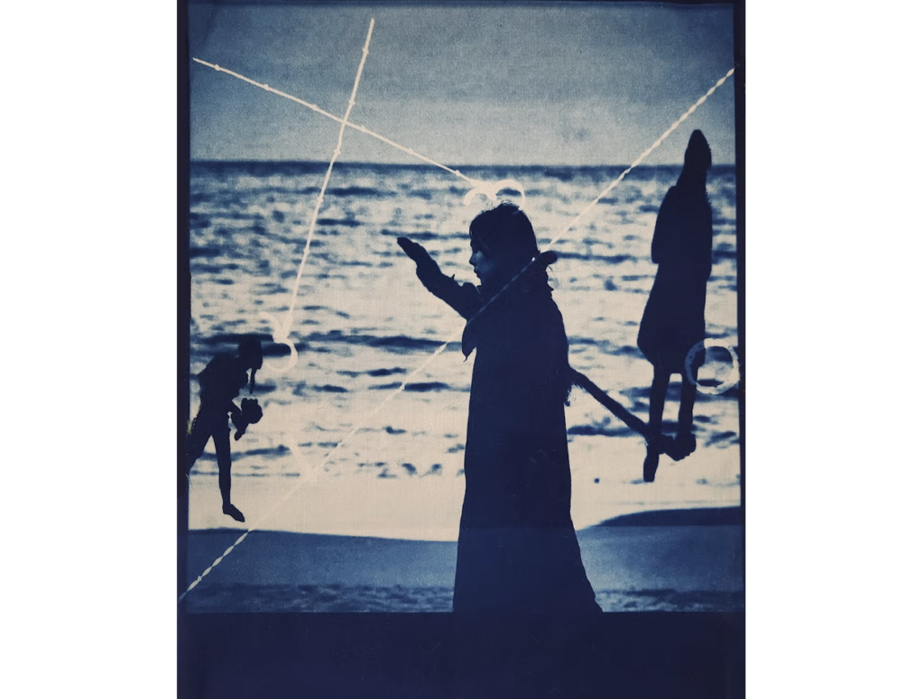 A cyanotype of a person silhouetted in front of the ocean.